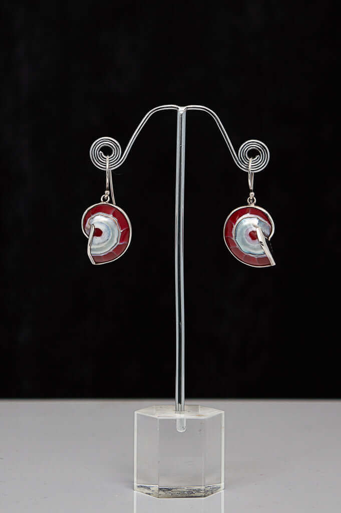 Pair of red and white spiral shell 925 sterling silver earrings displayed on a stand