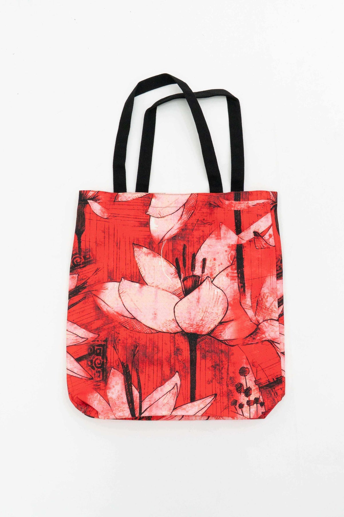 Red canvas tote bag with black handles and large bold lotus flower print