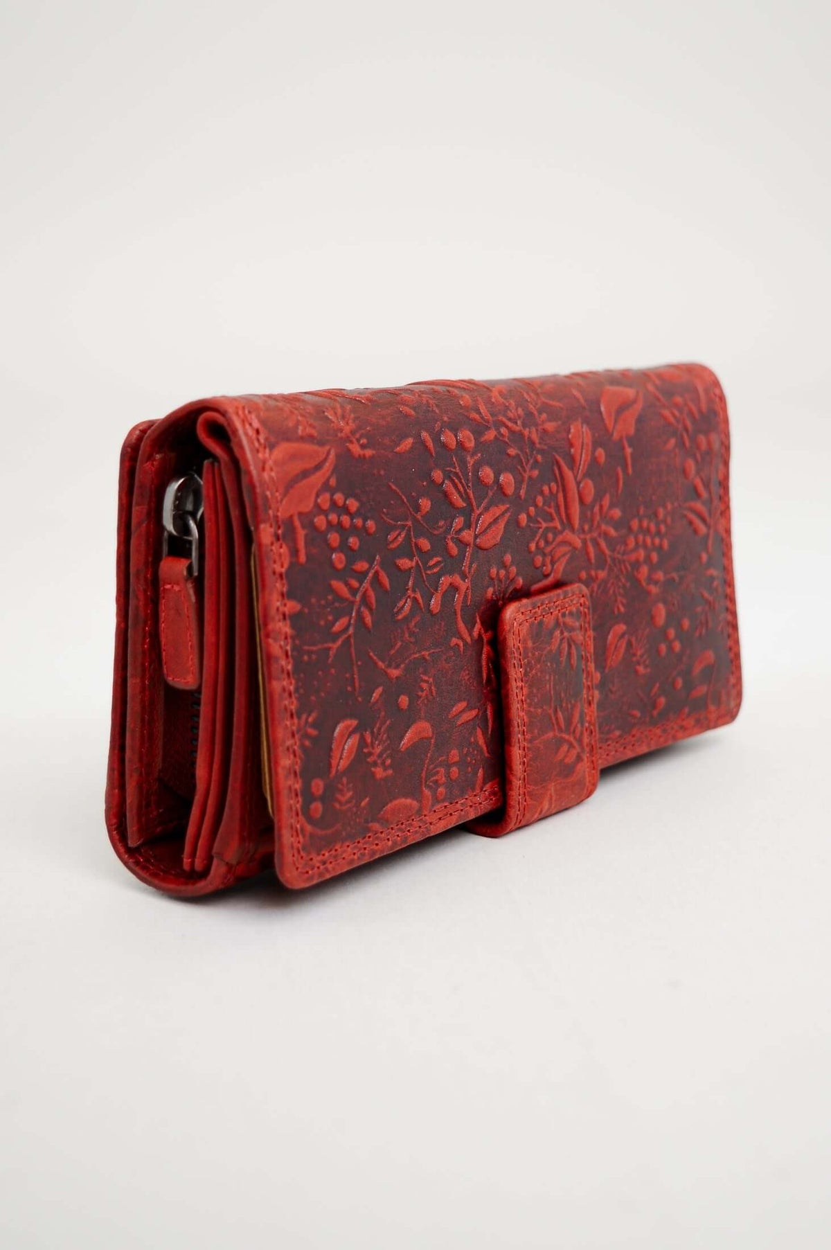 Side angle of a red embossed leather wallet with floral detailing