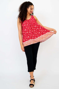 Woman holding out the hem of a red floral pleated tank top