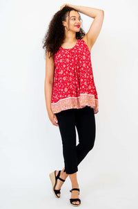 Woman in red floral pleated tank top with hand on head, side-facing view