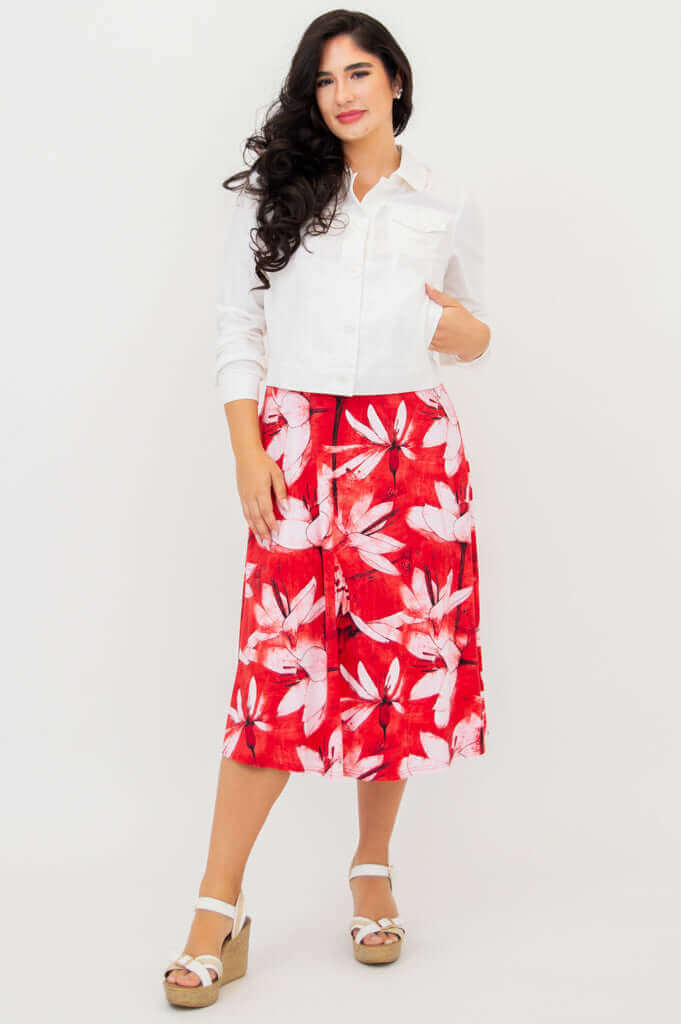 Woman with white jacket over red floral tank dress, hands in pockets