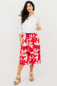 Woman with white jacket over red floral tank dress, hands in pockets