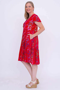 Side view of a woman in a red tiered dress with her hand in the pocket