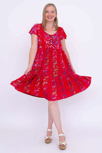 Woman twirling in a red tiered dress with flutter sleeves and vibrant floral pattern