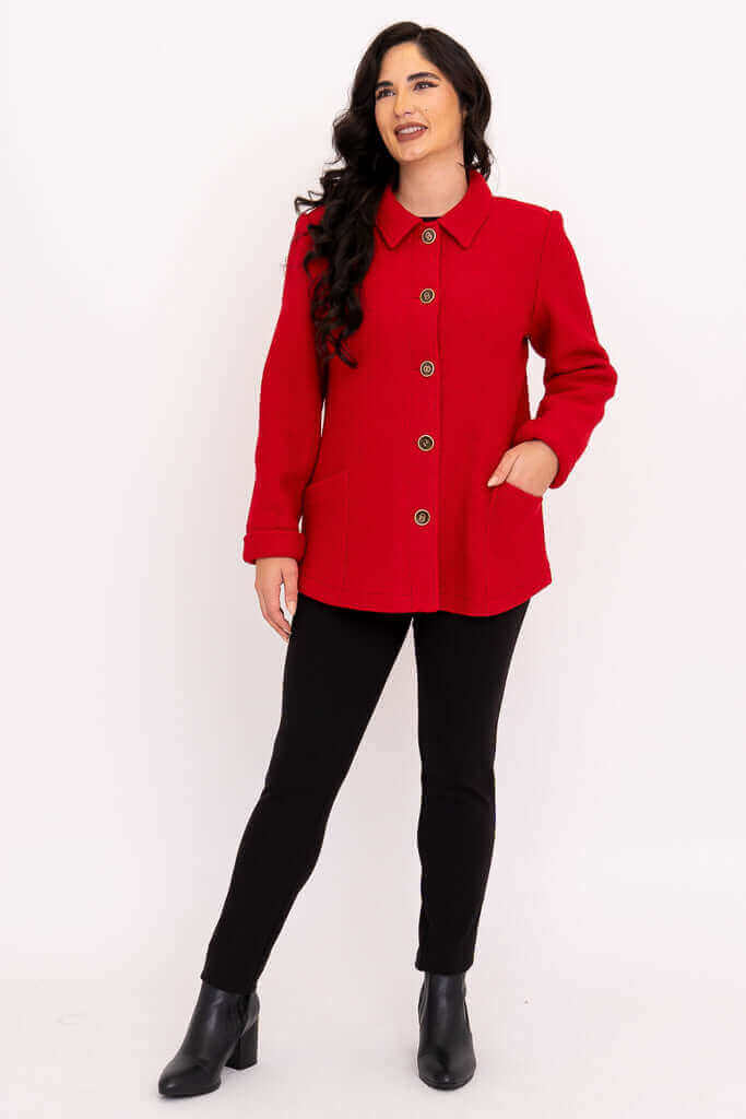 Woman standing in red wool blend coat with angled pockets and bronze buttons