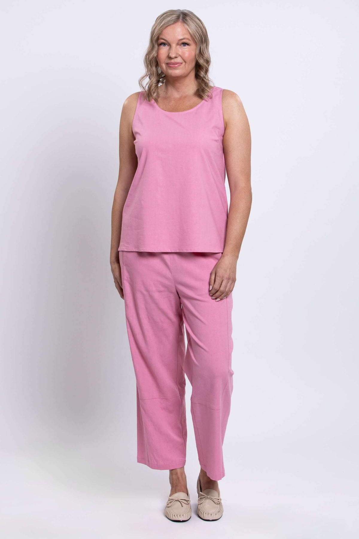 Woman standing in pink tank top and pants, relaxed fit, full length front view