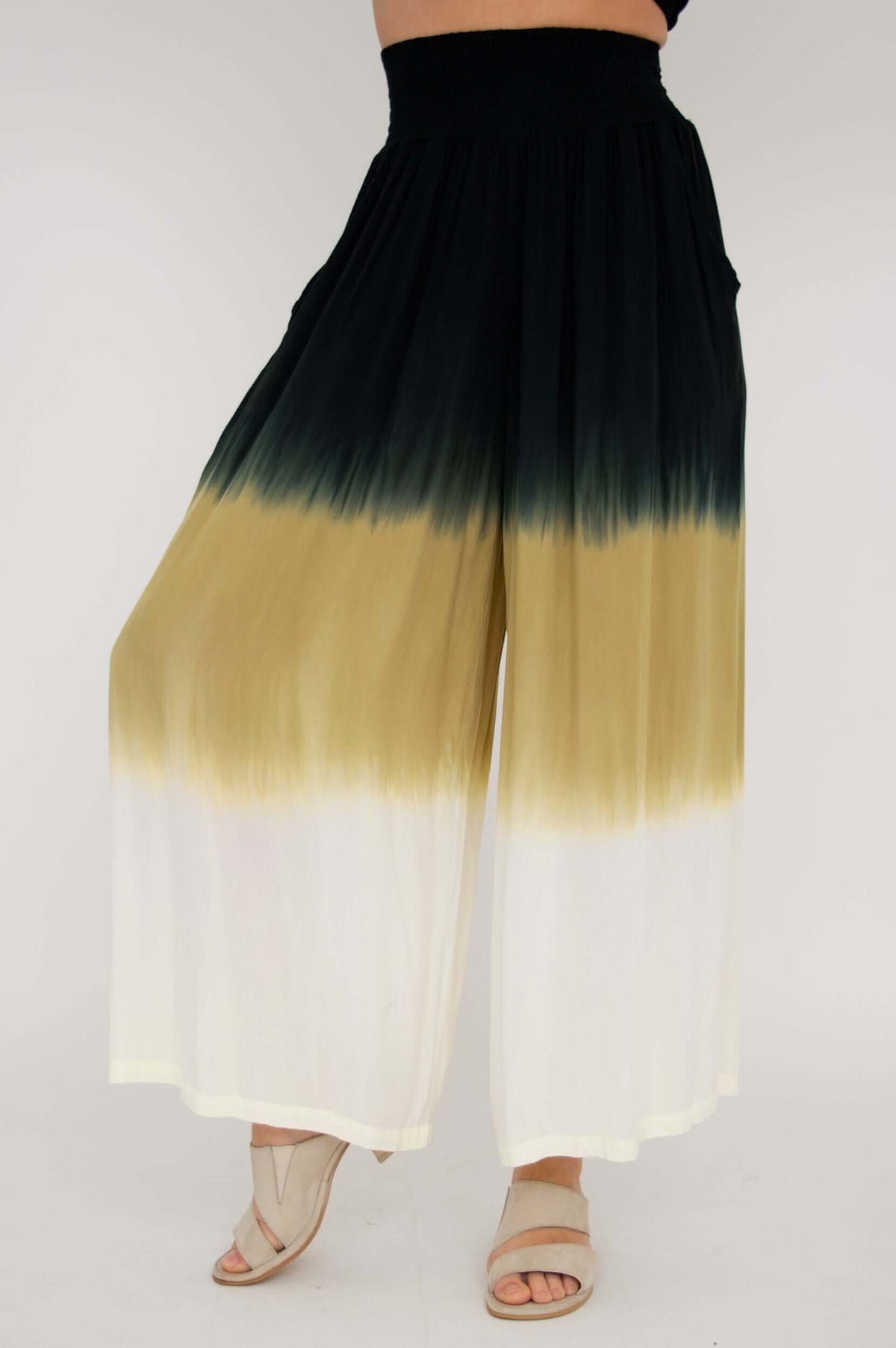 Wide-leg ombre pants with black, tan, and white color blocks in a relaxed pose