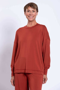 Woman wearing a relaxed fit rust-colored bamboo crew neck top and matching pants, smiling