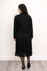 Back view of woman standing in formal black lace outfit featuring a matching cardigan and dress