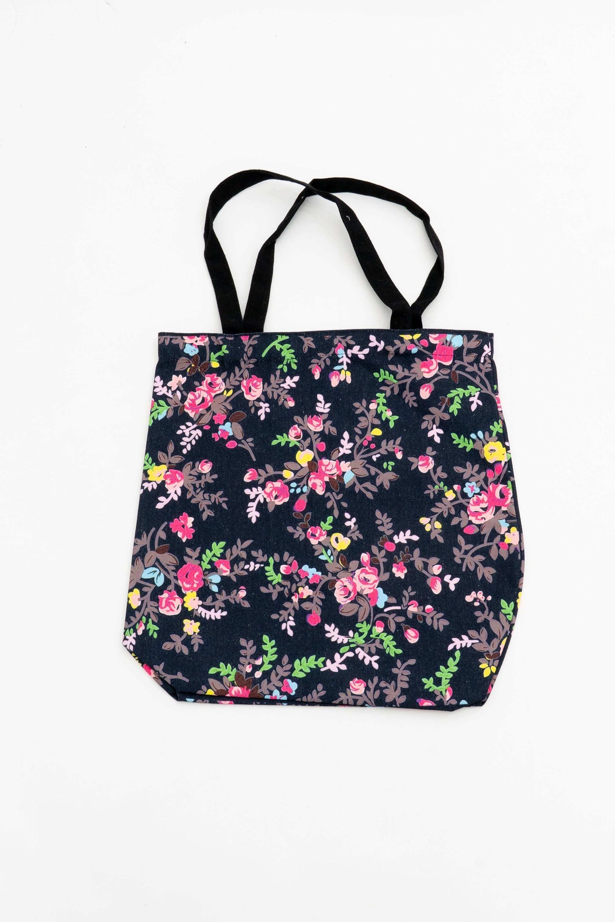 Reusable cotton tote bag with colorful floral camouflage-inspired print on dark background