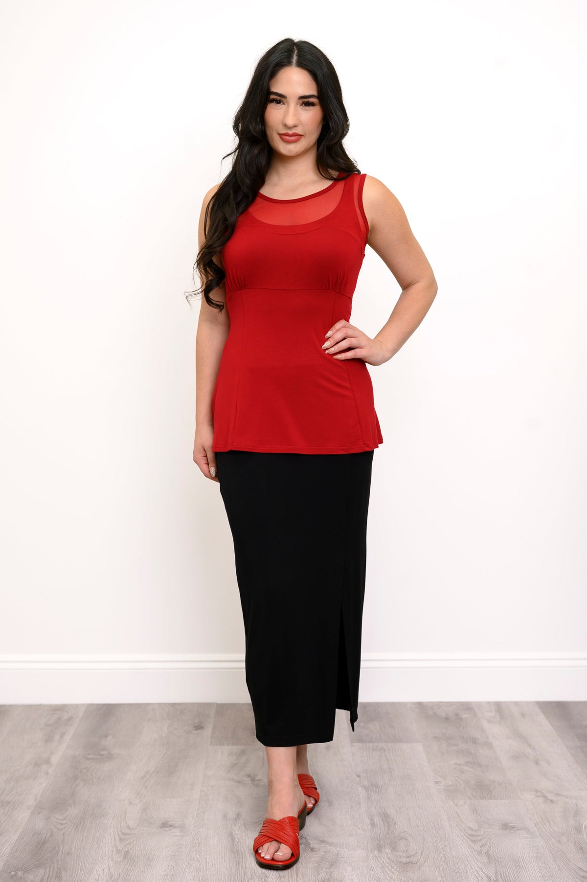 Full body view of model with her hand on her hip wearing a red tank top, black pencil skirt, and red shoes
