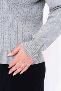Close-up of ribbed cuff and cable knit texture on grey sweater
