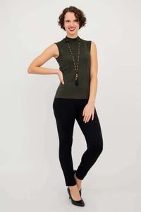 Woman in olive-green sleeveless mock neck sweater and black pants, hand on hip, full body