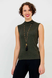 Woman smiling in sleeveless olive-green mock neck sweater and long beaded necklace