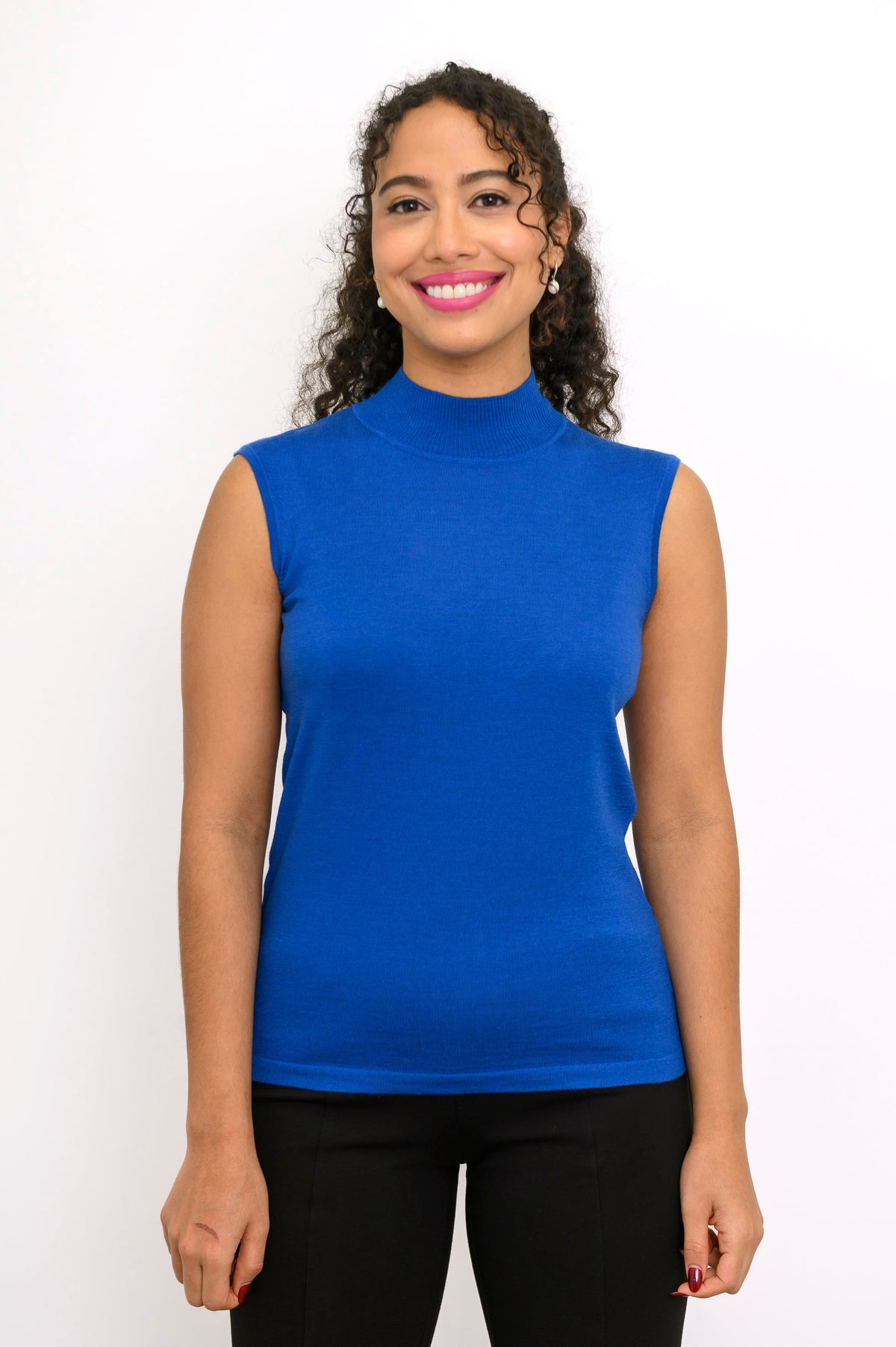 Studio portrait of a woman modeling a vibrant blue sleeveless knit top with a fitted mock collar.