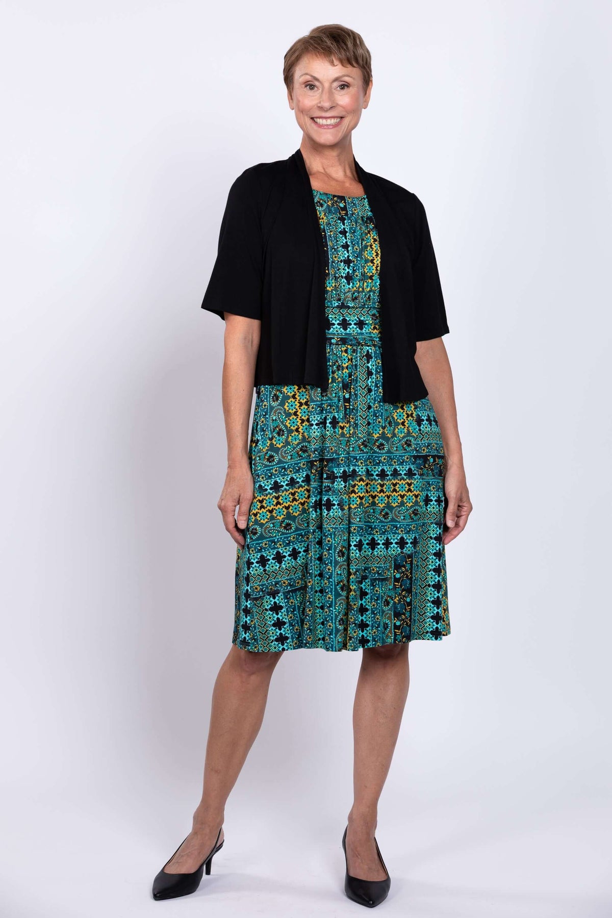 Woman modeling teal patterned dress with black cardigan and heels