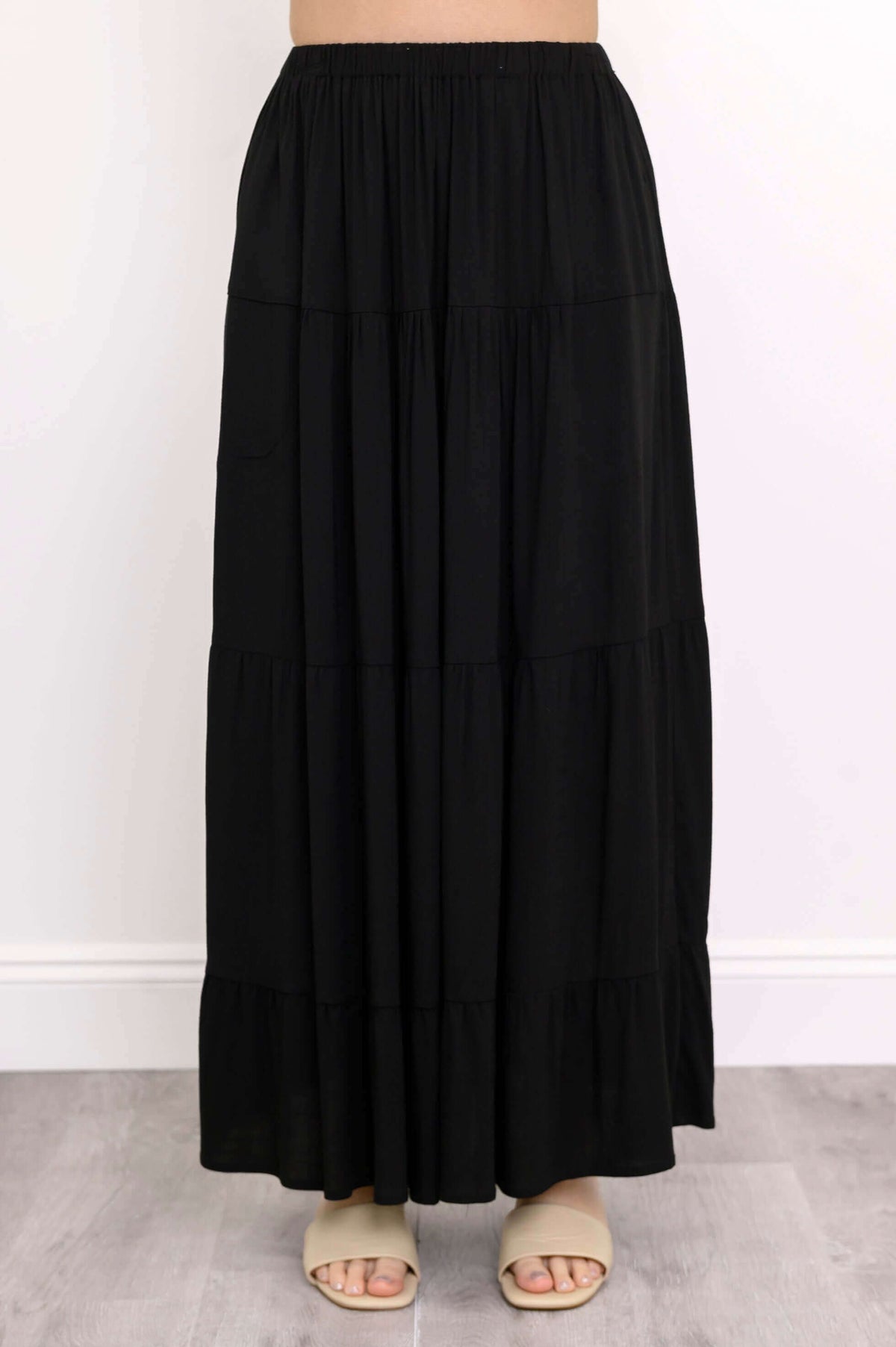 Front view of black tiered maxi skirt and beige sandals