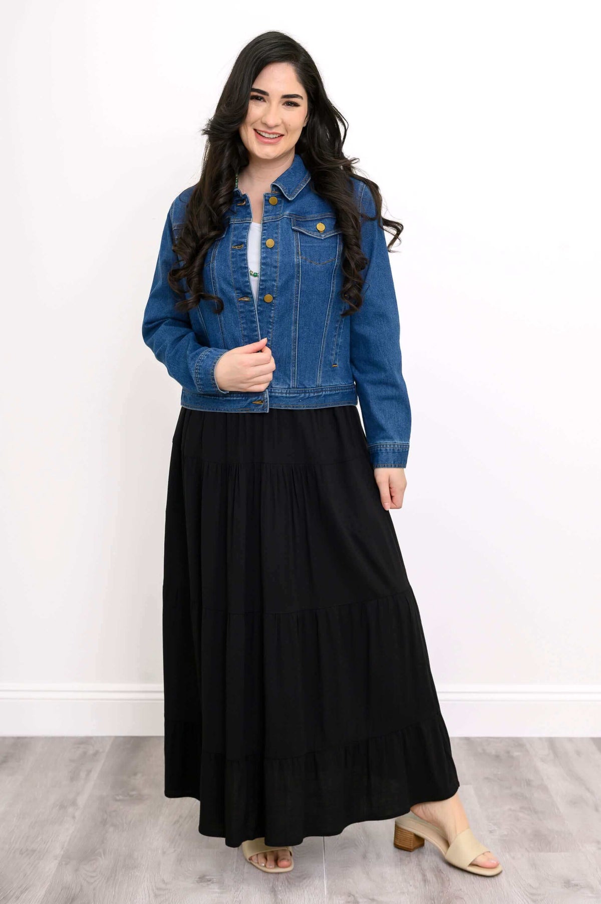Woman wearing a tiered black maxi skirt with denim jacket and sandals