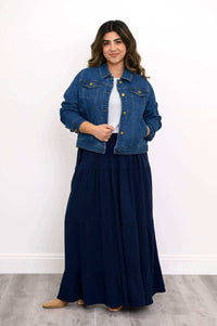 Model in navy tiered maxi skirt and denim jacket, front view with one hand on jacket