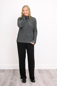 Model posing in a textured charcoal gray cotton sweater paired with tailored black pants, standing front-facing.