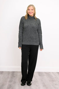 Model posing with hand on hip in a loose charcoal gray cotton sweater, showcasing its soft, relaxed drape.