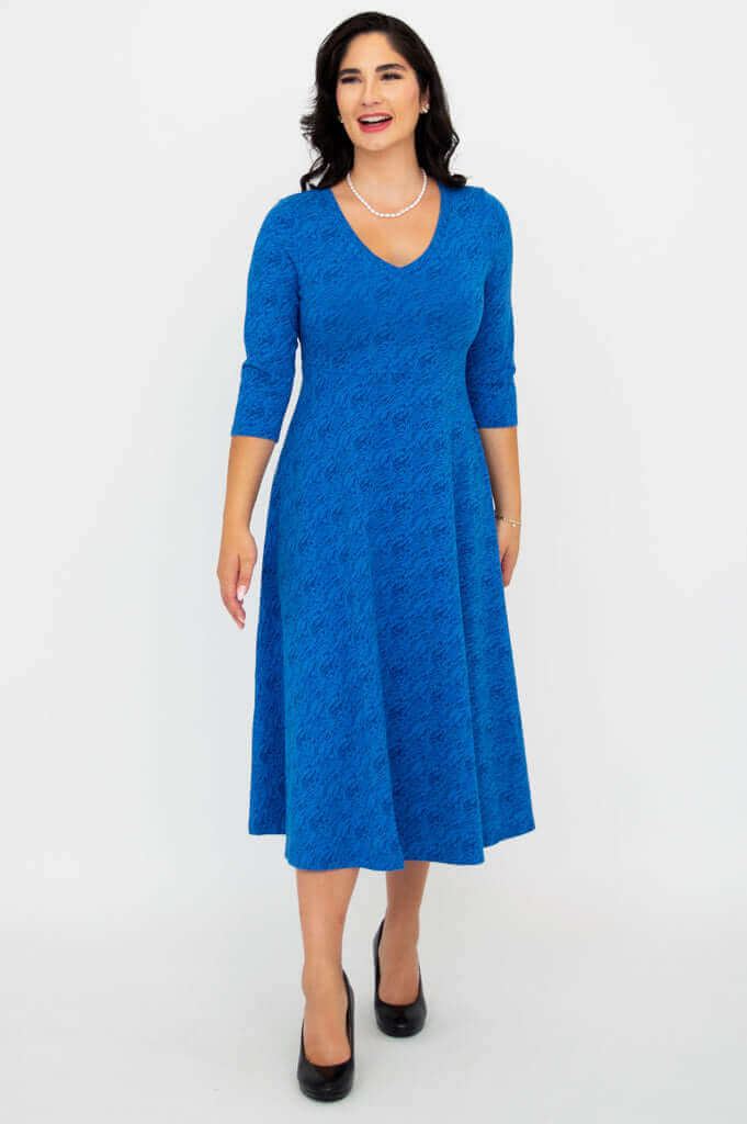 Woman smiling in a royal blue midi dress with a flowy skirt, V-neck, and 3/4 sleeves