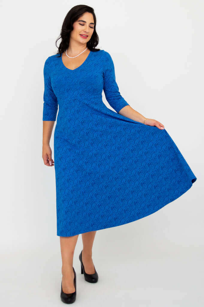 Woman in royal blue midi dress holding skirt to the side for a twirl effect