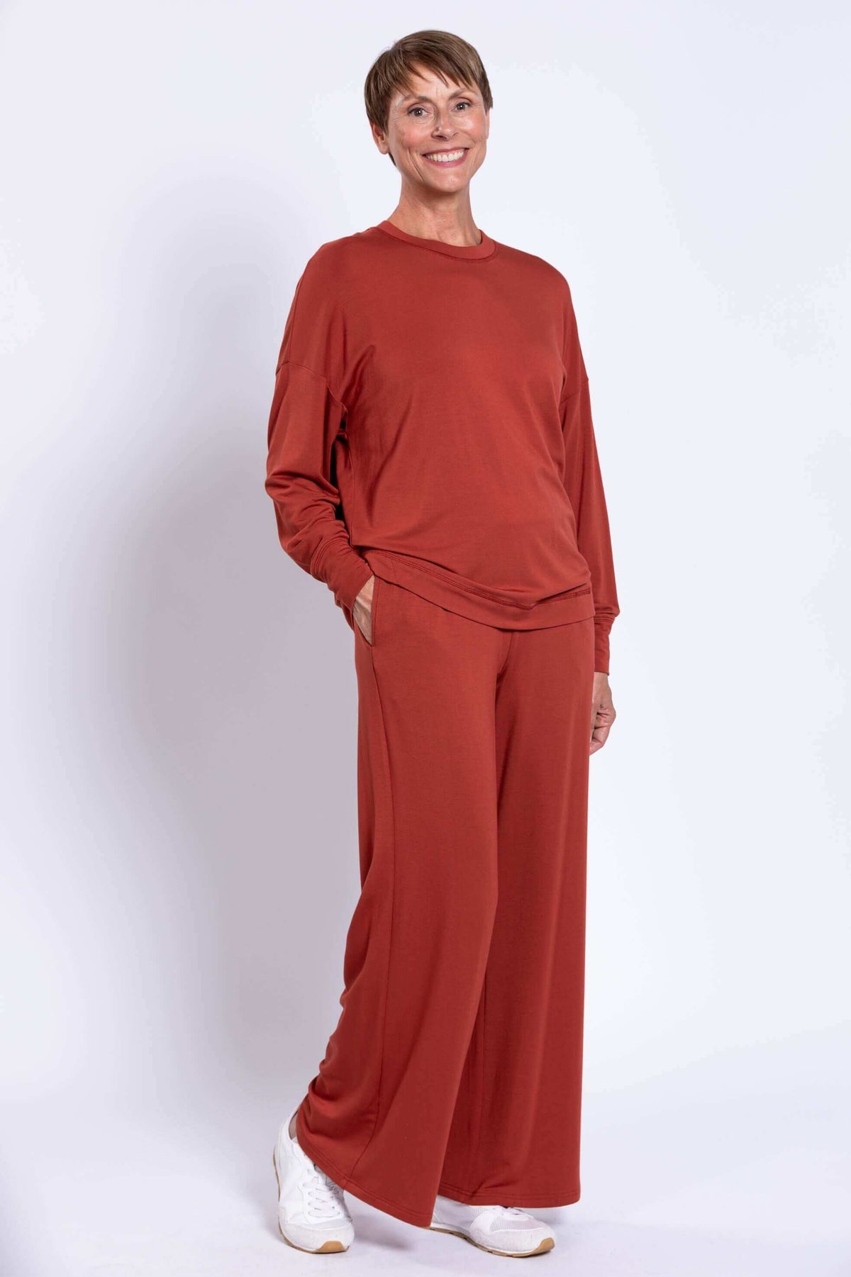Woman with hands in pockets, modeling rust bamboo crew neck top and pants