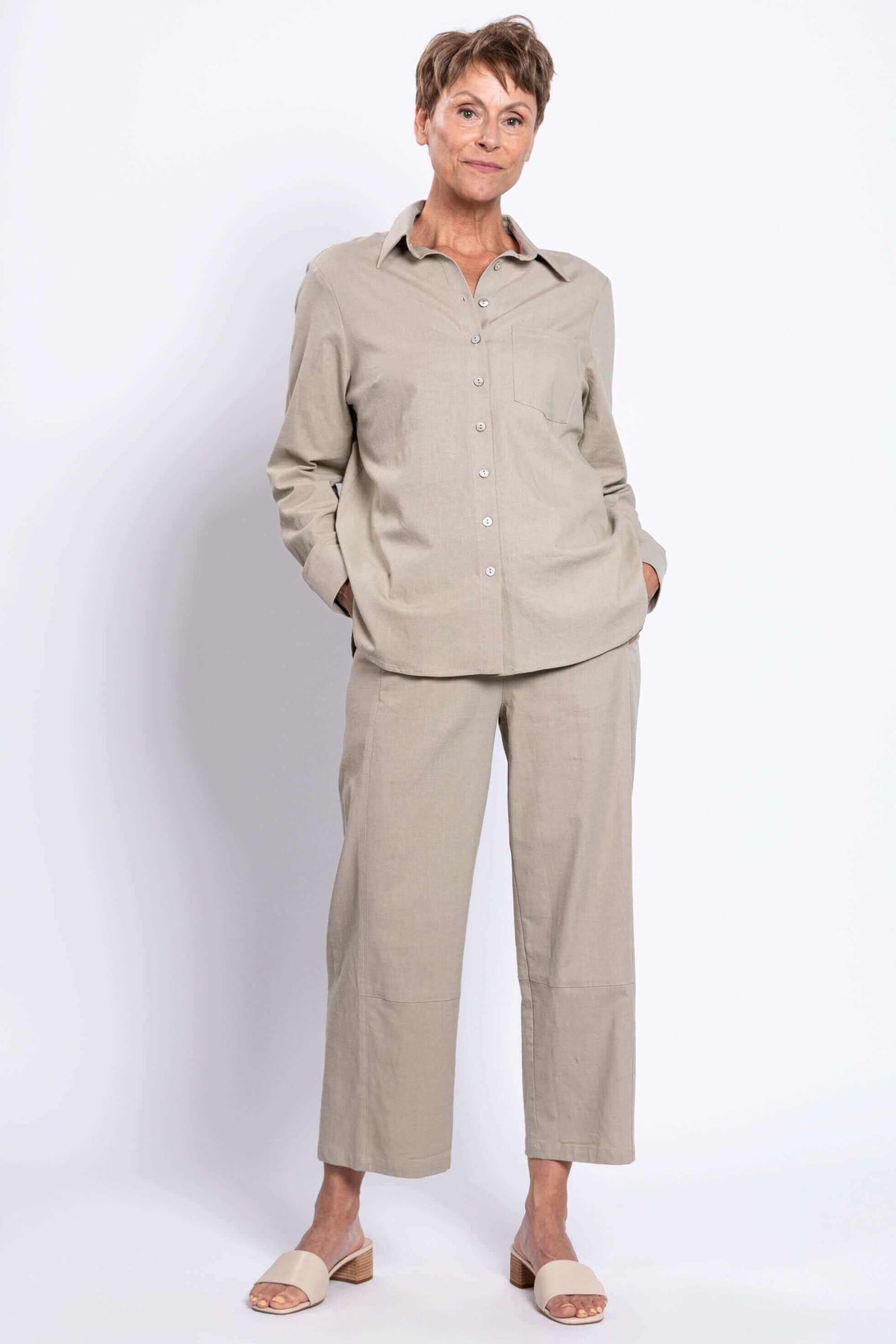 Woman standing with hands in pockets in sage relaxed linen shirt and pants