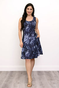 Full body view of woman posing with her hand in her pocket and wearing a dark blue floral dress