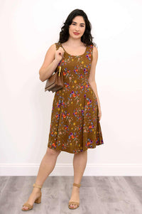 Woman with brown floral dress and tan handbag over shoulder