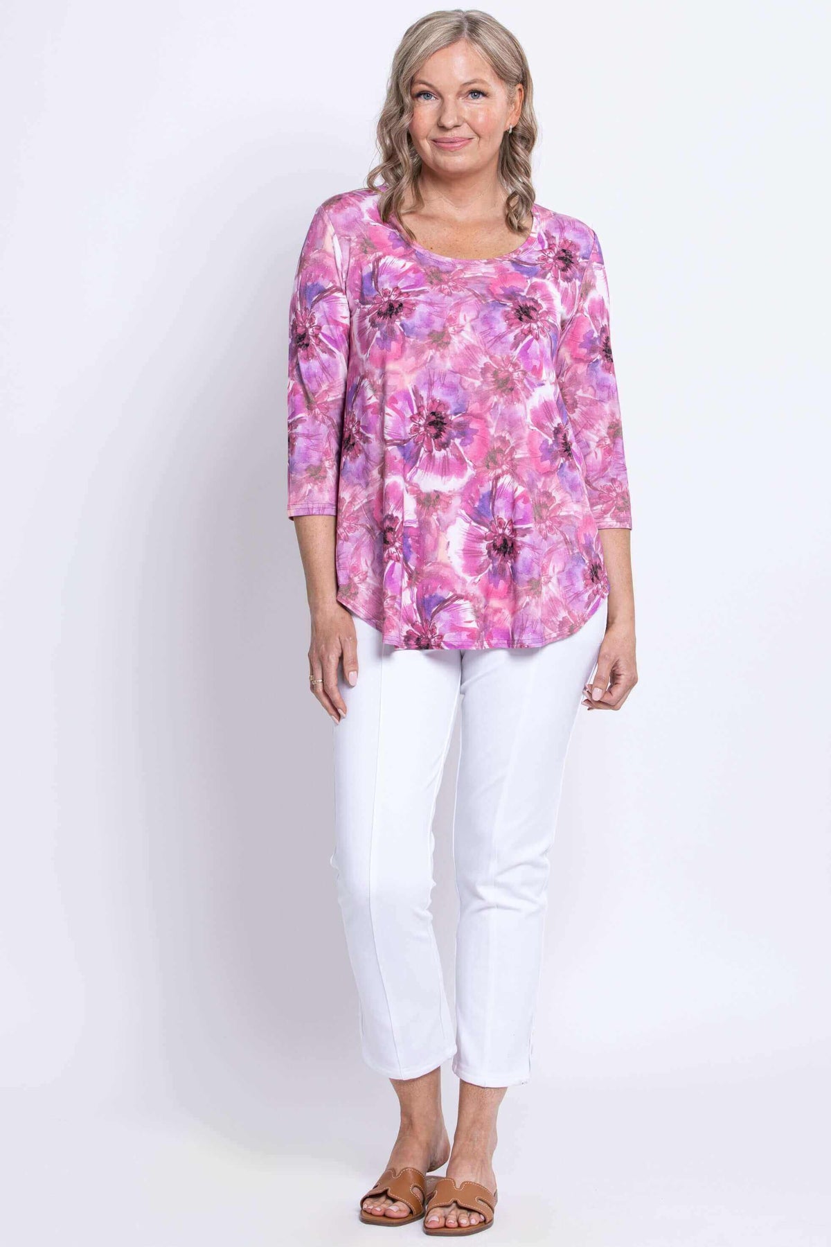 Semi-angled front view of woman in floral bamboo top with white pants