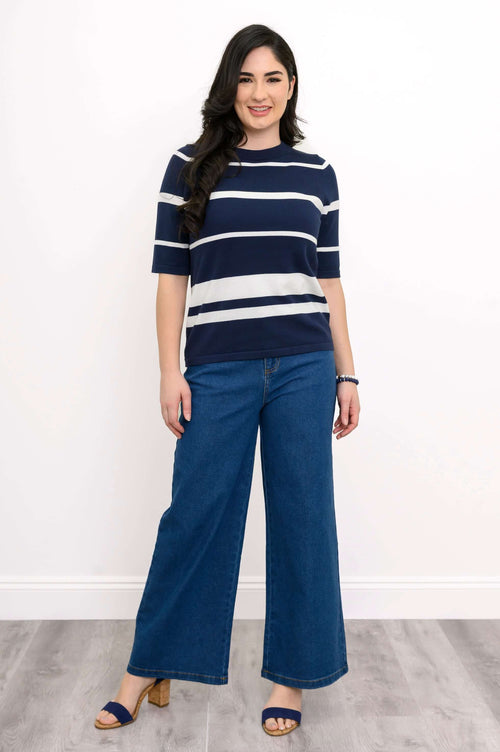 Woman smiling in classic navy stripe crew sweater and wide blue jeans, front-facing
