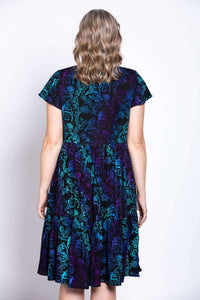 Back view of dress with blue and purple botanical print and flutter sleeves, model's hair curled