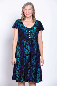 Front close-up of model in black dress with blue and purple print, featuring shell buttons and tie details