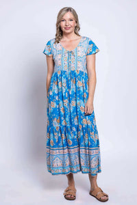Woman modeling blue Sharpie Dress with floral print, shell buttons, and string tie at neckline