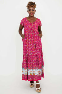 Model displaying pockets on a pink floral maxi dress with a patterned border