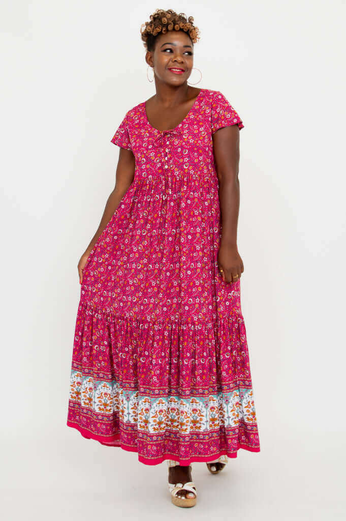 Model showing playful movement in a pink floral tiered maxi dress