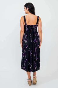 Back view of woman in sleeveless black dress with purple dragonfly pattern, showing shirred bodice