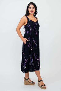 Side view of woman in sleeveless black dress with purple dragonfly print and pockets