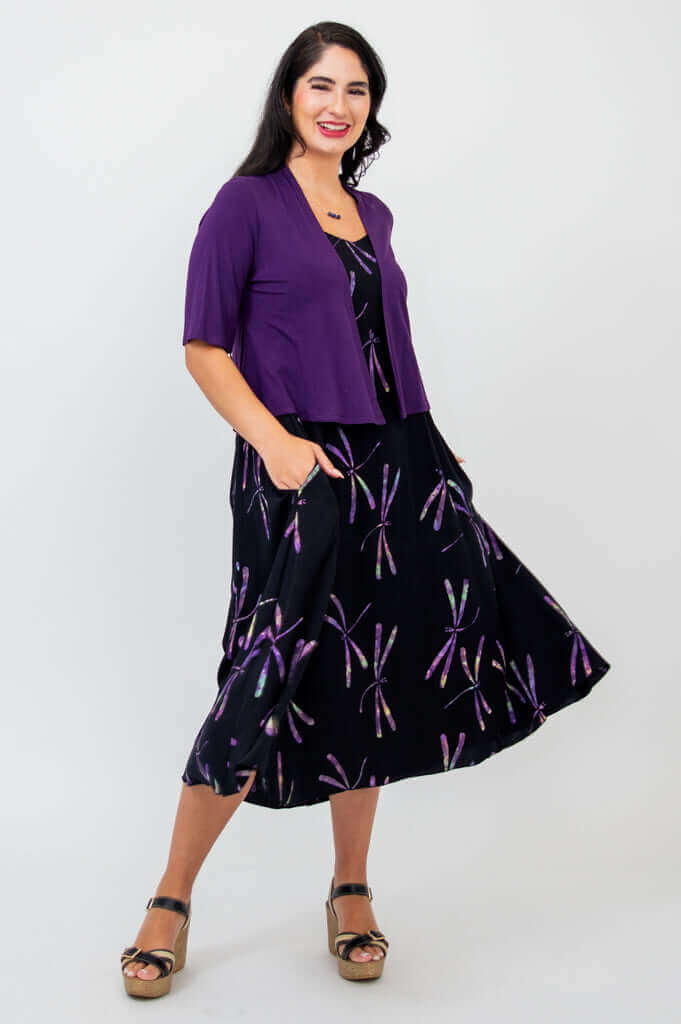 Woman twirling in black dress with purple dragonfly print and purple shrug