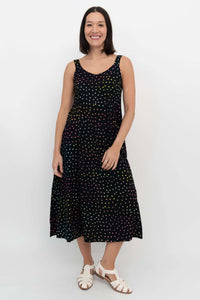 Woman smiling in a black polka dot midi dress with hands by her side