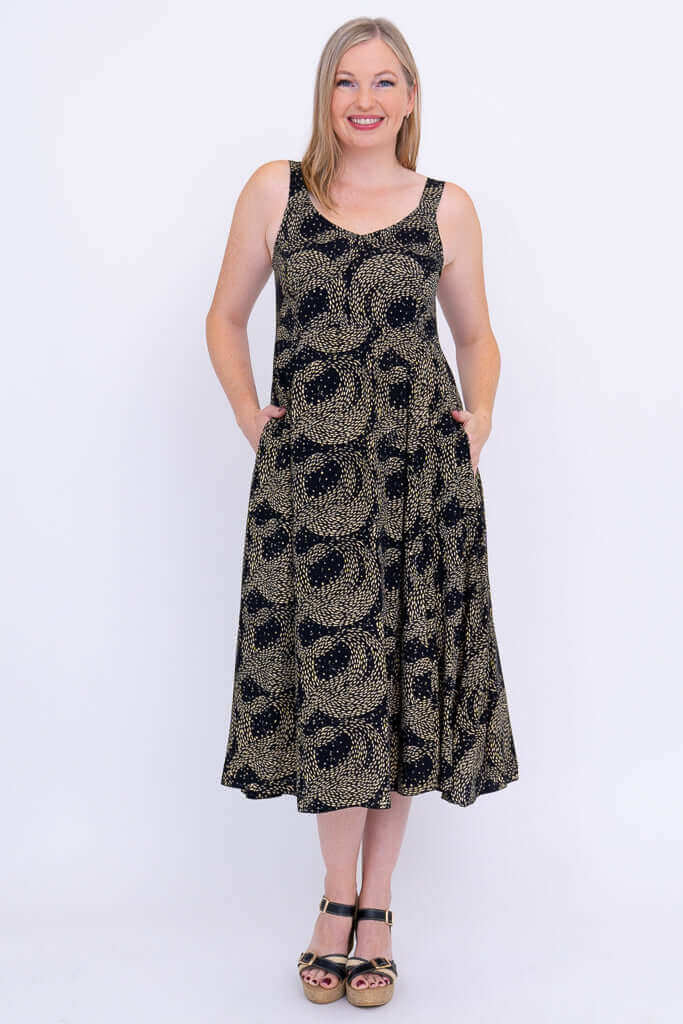 Front view of woman wearing the Shauna black and gold patterned sleeveless A-line dress