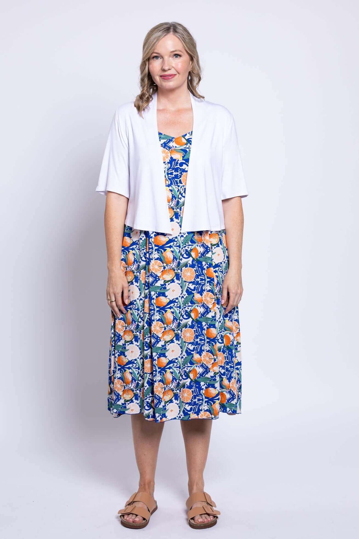 Woman wearing citrus floral sundress paired with a white shrug