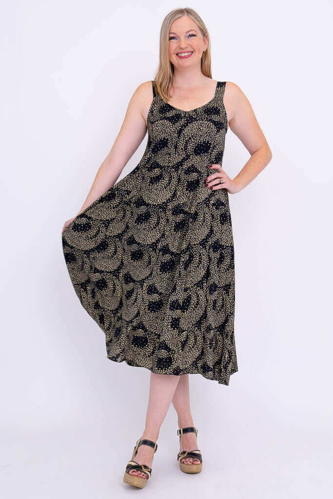 Woman holding out skirt of black and gold Shauna dress, showing A-line silhouette