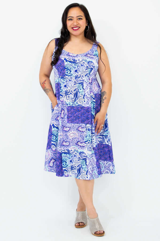 Woman posing with hands in pockets wearing a blue and purple sleeveless patchwork dress