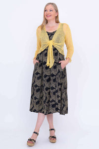 Woman in Shauna dress styled with a yellow long sleeve shrug, hands in pockets