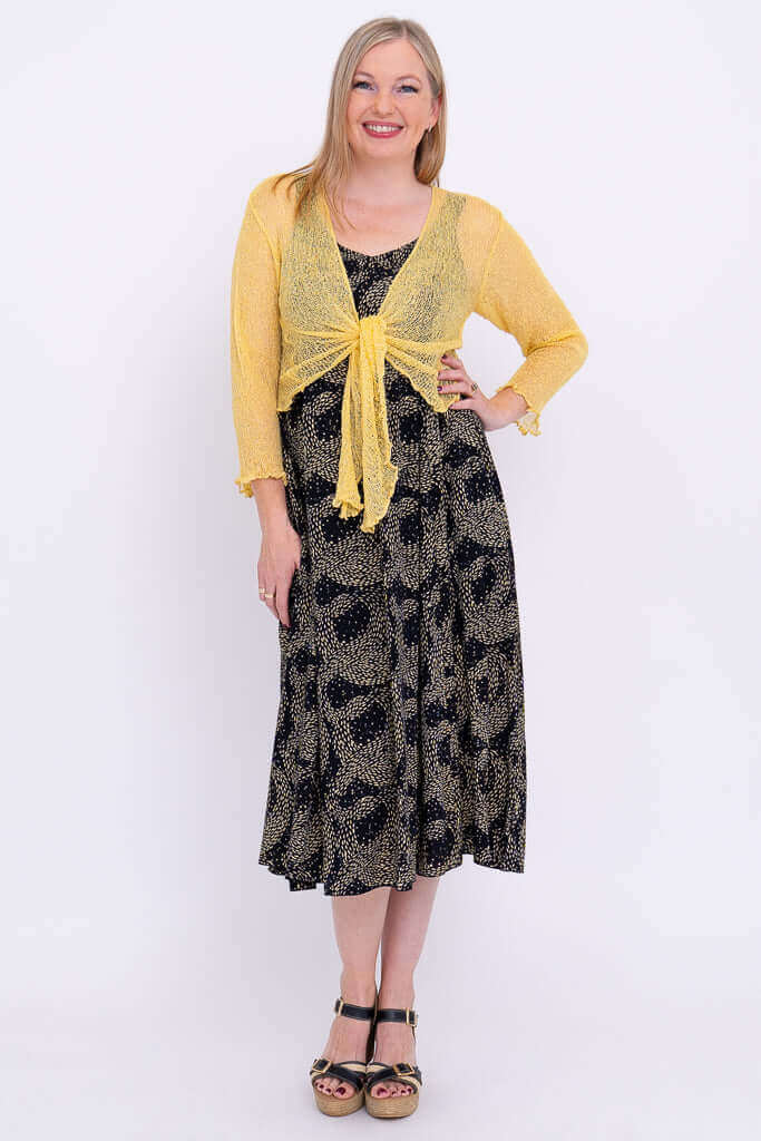 Front view of Shauna dress paired with yellow shrug, hands on hip and pocket