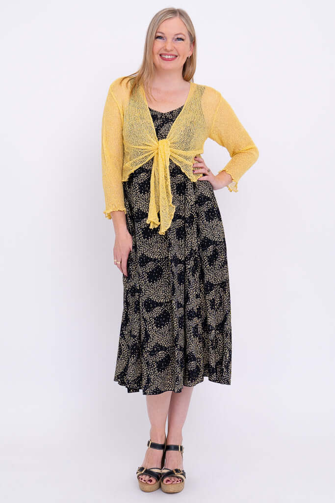 Model wearing the Shauna midi dress and a yellow cardigan, posing hand on hip